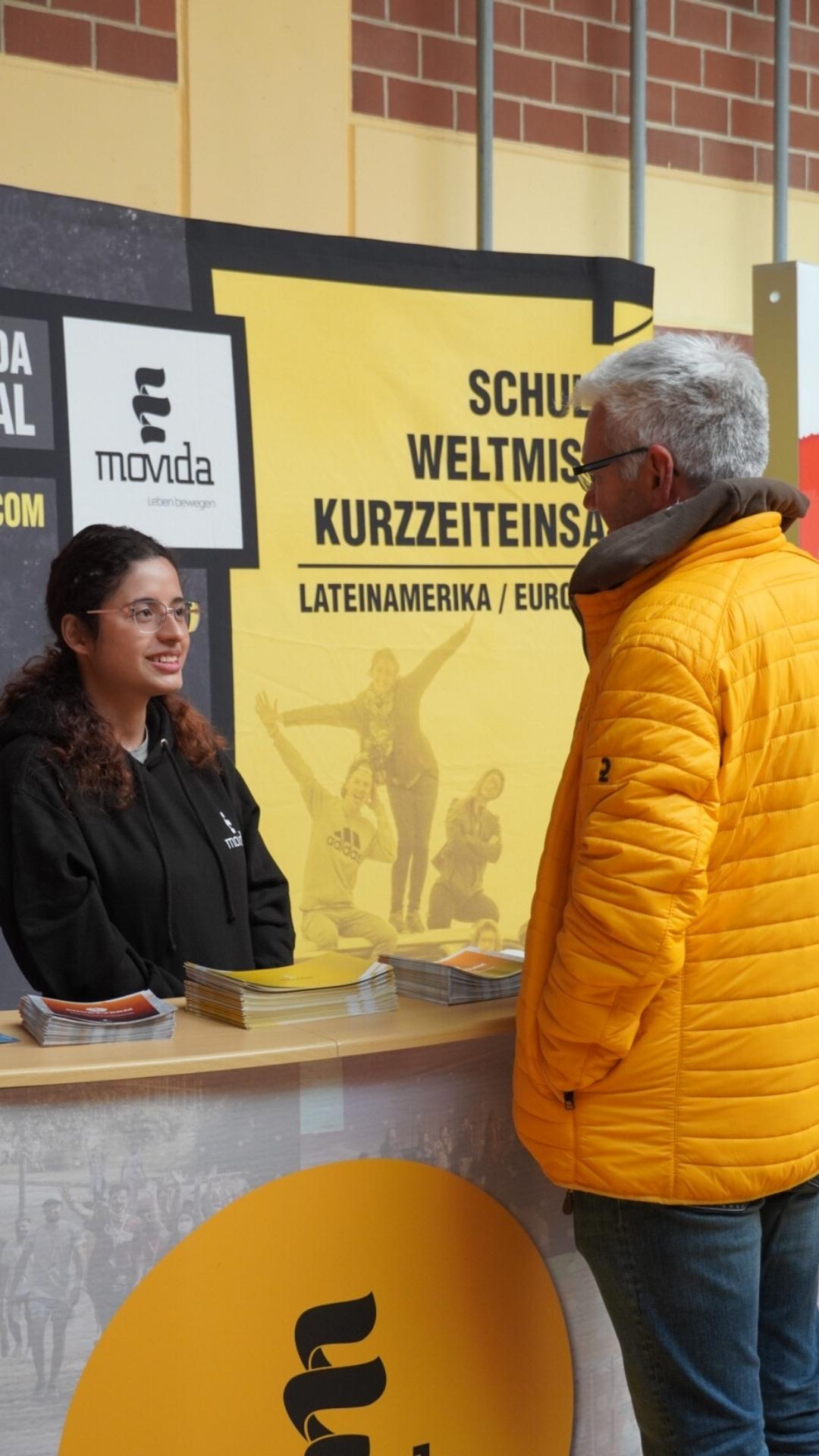 Gespräch am Movida-Stand zwischen einem Mann und einer Missionarin – JUMIKO 2024